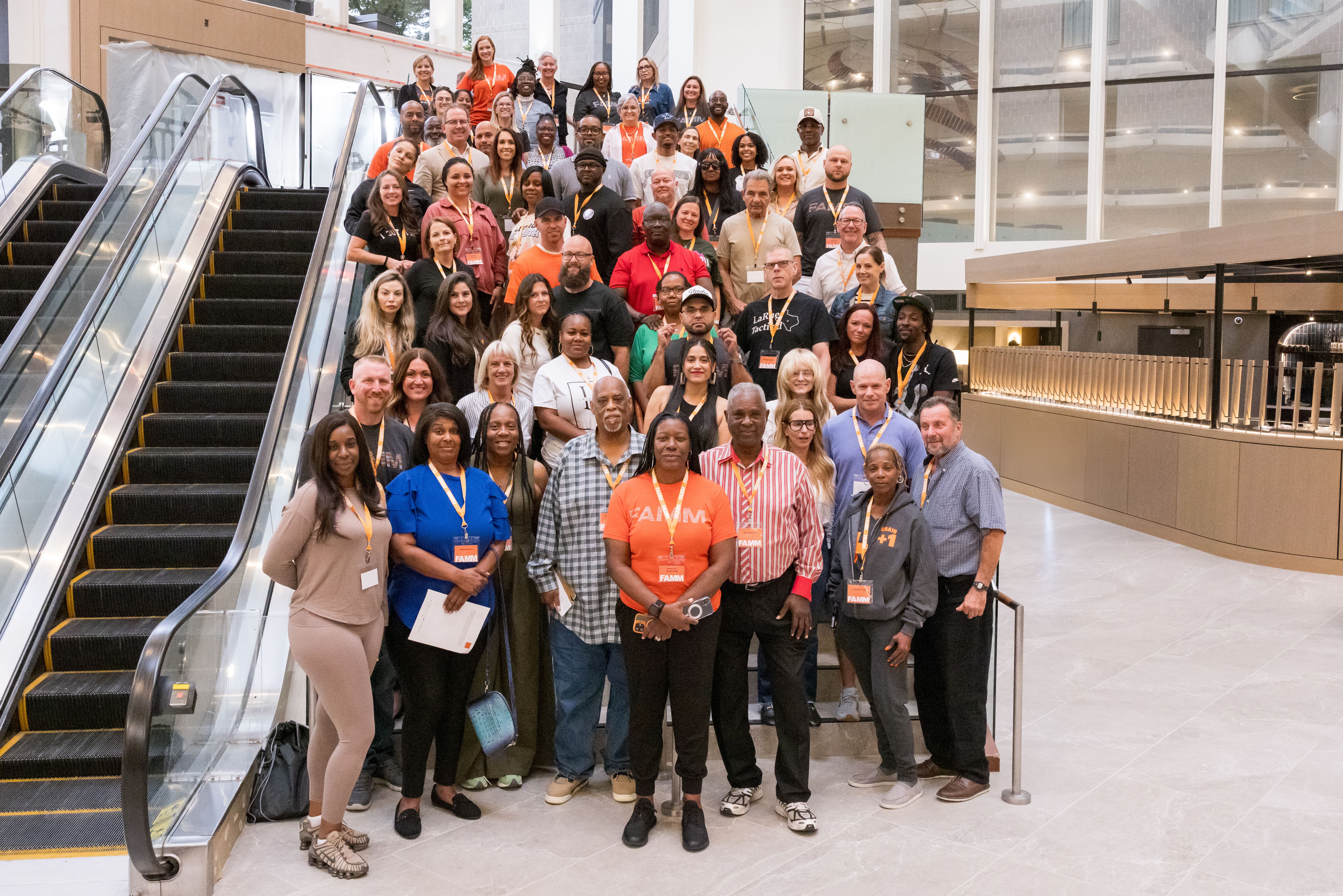 Large group of attendees gathered on stairs next to an escalator for a group photo at an event.